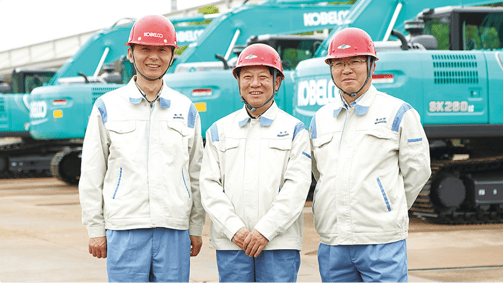 成都での工場復旧と再稼働を牽引した神鋼建機(中国)有限公司のリーダー3名。背景にはコベルコ建機のショベルカーが並んでいる。