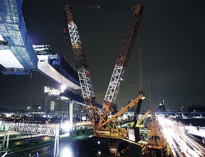 コベルコ建機の大型クローラークレーンによる夜間の橋梁架設工事現場