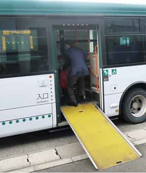 車椅子利用者を補助しシャトルバスへ案内する係員。