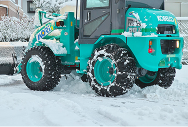 タイヤチェーンを装着して雪道を走行するミニホイールローダ。