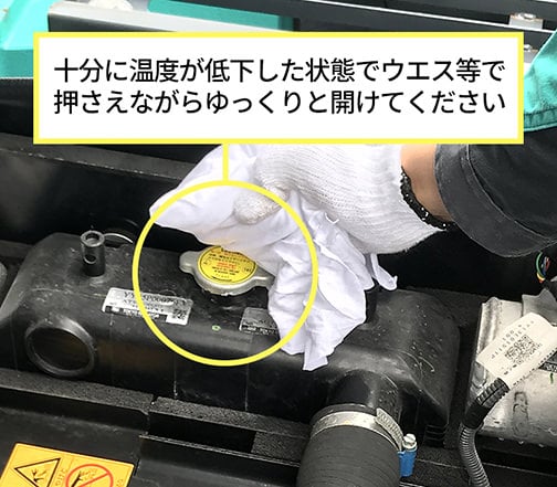 蒸気による火傷を防止するラジエータキャップの開け方。ウエスを使いながらゆっくりとキャップを開けようとしている作業写真。