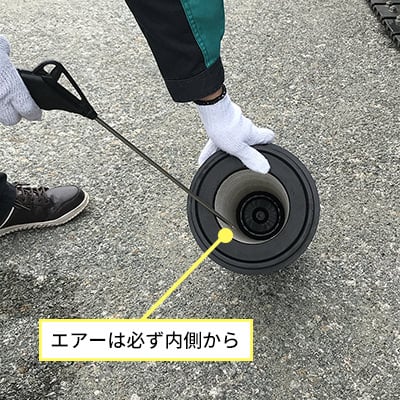 状のフィルタ内部にエアガンを差し込み、内側から外側へ向けて清掃している写真。
