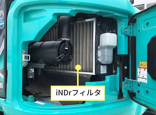 ショベルのエンジンルーム内にある「iNDrフィルタ」を指し示している写真